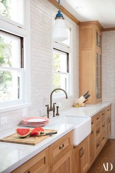 a kitchen with wooden cabinets and white marble counter tops, along with watermelon slices on the cutting board