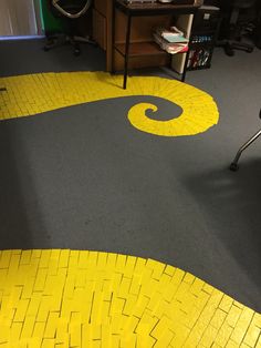 a room with yellow and black tiles on the floor next to a computer desk in front of a bookcase