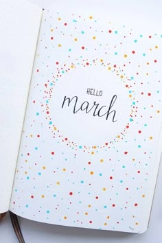 an open notebook with the word hello march written in black on it and colorful confetti