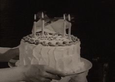 two people holding a cake with candles on it