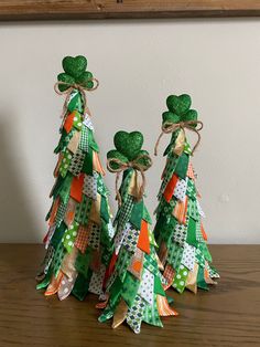 three green and gold christmas trees with shamrocks on them sitting on a wooden table