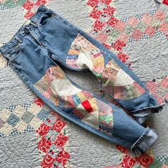 two pairs of blue jeans are laying on a quilted bed spread with an old patchwork design