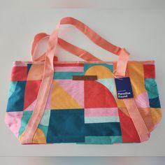 a multicolored bag with a tag hanging from it's side on a white surface