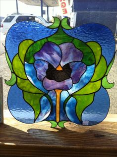 a stained glass window with an image of a flower on the outside, and green leaves