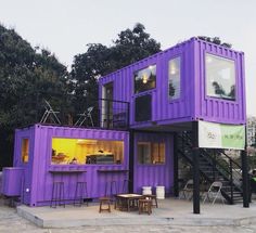 purple shipping containers are stacked on top of each other in front of a building with stairs leading up to the second floor