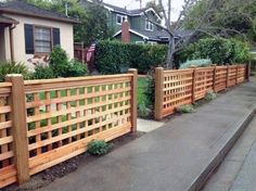 a wooden fence next to a sidewalk in front of a house