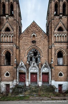 an old church with two red doors and some steps leading up to the front door