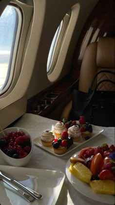 two plates with desserts on them sit next to each other in front of an airplane window