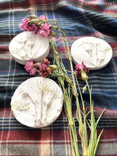 three soaps with flowers sitting on a plaid cloth