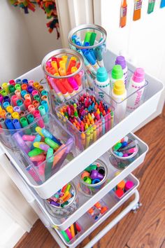 an organized drawer with markers, crayons and pencils on the bottom shelf