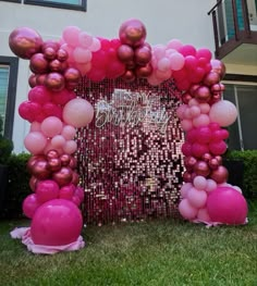 a pink and gold balloon arch in front of a house