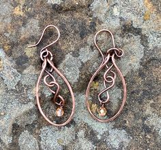 Hammered Copper with copper figure eights and flame colored crystal dangles. Come on handmade copper ear wires.Approximately 2" long from the top of the ear wire and 13/16" wideThese Earrings have been antiqued, polished and sealed.Sealed with Protectaclear ProtectaClear is a clear, protective coating that is tough enough to protect jewelry and is safe for wear against skin. ProtectaClear is practically invisible once applied and will seal and protect jewelry from tarnish, oxidation, and corrosi Colored Wire Jewelry, Bronze Teardrop Copper Earrings, Bronze Copper Teardrop Earrings, Copper Teardrop Dangle Earrings, Hand Forged Copper Wire Drop Earrings, Hand Forged Bronze Earrings With Copper Wire, Bronze Wire Wrapped Copper Earrings, Bronze Wire Wrapped Teardrop Earrings, Hammered Copper Jewelry