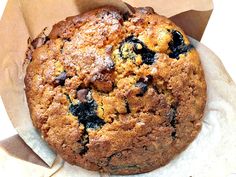 a muffin sitting on top of a piece of wax paper next to a bag