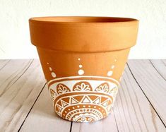 a clay pot sitting on top of a white wooden table next to a planter