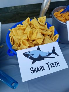 a bowl full of chips next to a sign that says shark teeth and some other snacks