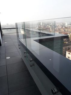 an empty balcony with glass railings overlooking the city