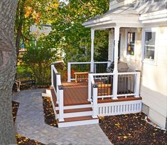 a small white house with steps leading up to the front door and covered porch area