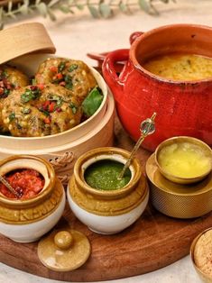 an assortment of food is displayed on a wooden platter with sauces and condiments