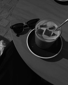 a person sitting at a table with a drink in front of them and sunglasses on it