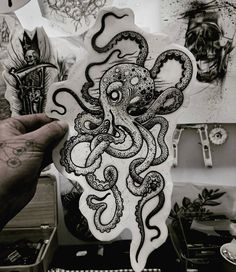 an octopus sticker is being held up by someone's hand with tattoos on it