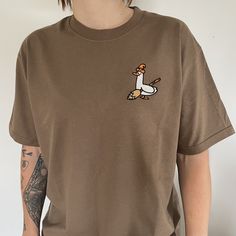 Brown organic t shirt with an embrodiered silly goose  Witchy Silly Goose T- Shirt with Halloween theme embroidery design. 👻 Unisex relaxed fit  ✨Classic silly goose dressed and ready for Haloween! Witchy goose✨ If you would like a size or colour that you can't see here then please don't hesitate to message us as we would love to try to accommodate your request as best we can 😊  ✨By buying a little something from us you will supporting a small business (entirely ran by just 2 lovely ladies ️)! Custom Embroidery Relaxed Fit T-shirt For Fall, Fall T-shirt With Embroidered Text And Relaxed Fit, Embroidered Relaxed Fit T-shirt For Fall, Fall Embroidered Graphics Short Sleeve T-shirt, Fall Embroidered Short Sleeve T-shirt, Embroidered Short Sleeve T-shirt For Fall, Custom Embroidery Short Sleeve T-shirt, Casual Embroidered Halloween T-shirt, Goose Dress