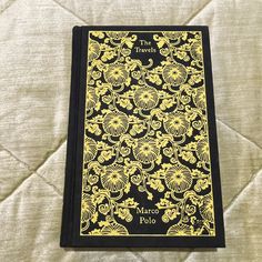 a black and yellow book sitting on top of a bed