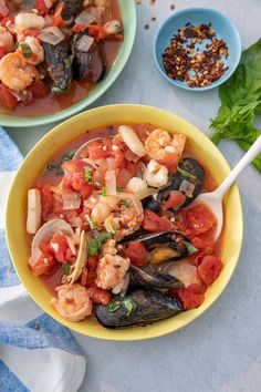 two bowls of seafood and vegetable soup on a table