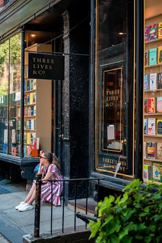 a woman sitting on a bench in front of a book store