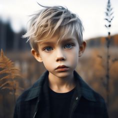 a young boy with blonde hair and blue eyes standing in front of some tall grass