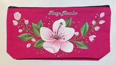 a pink purse with white flowers painted on the front and green leaves in the back