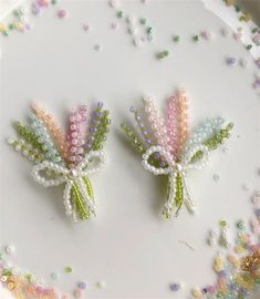 two beaded flowers sitting on top of a white plate