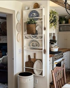 a kitchen filled with lots of dishes on top of a white book shelf next to a wooden table