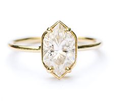 a yellow gold ring with an oval cut diamond in the center, on a white background