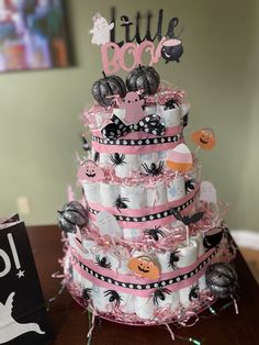 a pink and black diapered cake with decorations on the top is sitting on a table