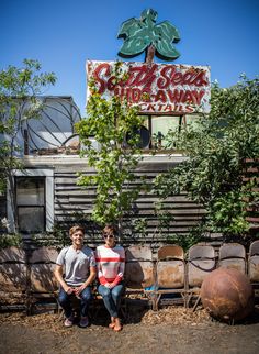 two people sitting in front of an old trailer