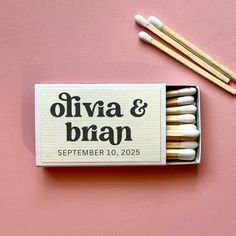 matchbox with matches on pink surface next to two wooden sticks and one box that says, oliva & bran