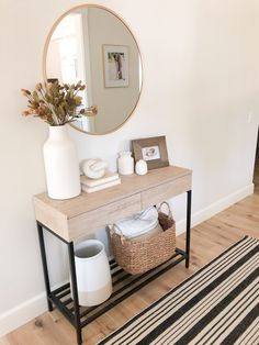 a white vase sitting on top of a wooden table next to a black and white rug