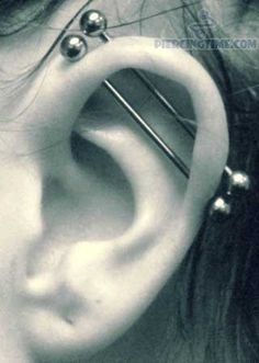 a close up of a person's ear with some piercings on it,