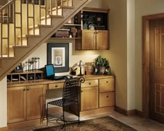 a computer desk under a stair case next to a wooden door and some shelves on the wall