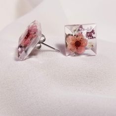 Beautiful, incredibly lightweight floral earrings. A soft red and deep purple flower. Square, multi-dimensional stud. Made with a clear, jewelry grade resin. Surgical steel, nickel free findings. NOTE: This is a handmade item and due to the uniqueness of handmade jewelry and materials some designs vary. I aim to keep the aesthetic of the original design and colors as similar as possible. Processing time is 2-3 weeks. I am occasionally able to do rush orders. Please feel free to contact me with any questions. I also do custom orders! Don't see a color combo you like? Have a new idea? Please contact me! Pink Flower-shaped Resin Jewelry, Pink Resin Flower-shaped Earrings, Pink Flower-shaped Earrings With Pressed Flowers, Pink Flower Earrings With Pressed Flowers, Hypoallergenic Clear Resin Earrings, Clear Hypoallergenic Resin Earrings, Pink Pressed Flower Earrings For Gift, Pink Resin Jewelry With Pressed Flowers, Red Pressed Flowers Earrings For Gift