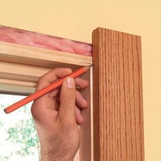 a person is holding a pencil in their right hand and sticking it into the window sill