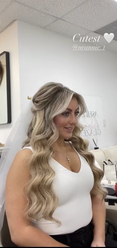 a woman with long blonde hair wearing a wedding veil and sitting in an office chair