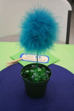 a table with a blue centerpiece and green place mat on it, next to a black cup filled with ice