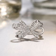 Give her all your love tied up with a glistening bowknot ring. It features a ribbon that twists and twirls into a charming bow at the center. Standing atop a polished shank, this lovely design makes an elegant accessory. Sparkling stones add an element of glamour to this feminine design.Carat Weight: 0.97 ctStone Size: 1.1,1.2 mmStone Type: Jeulia® StoneNumber of Stones: 78 Stone Color: Diamond WhiteStone Shape: RoundWeight: 4.79 gWidth: 14.2 mmHeight: 8.3 mmThickness: 2.5 mmMaterial: 925 Silver Diwali Jewellery, Bow Fashion, Silver Cocktail, Fine Jewelery, Bow Ring, Bow Jewelry, Silver Jewellery Sets, Purse Jewelry, Feminine Design