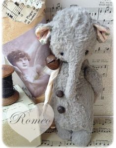 a gray teddy bear sitting on top of sheet music