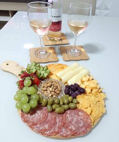 an assortment of cheeses, crackers, grapes and meat on a platter