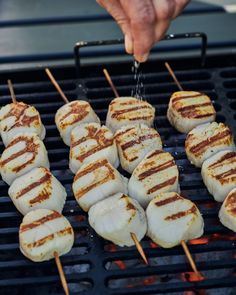 someone is cooking food on the grill with skewered meats and sauce being drizzled over them