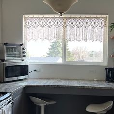 a kitchen with two stools in front of the counter and a microwave on the wall