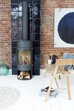 a wood burning stove sitting in front of a brick wall next to a chair and table