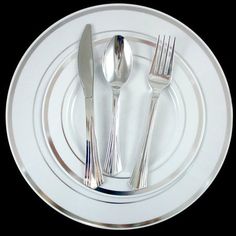 a white plate topped with silverware on top of a black table next to a knife and fork